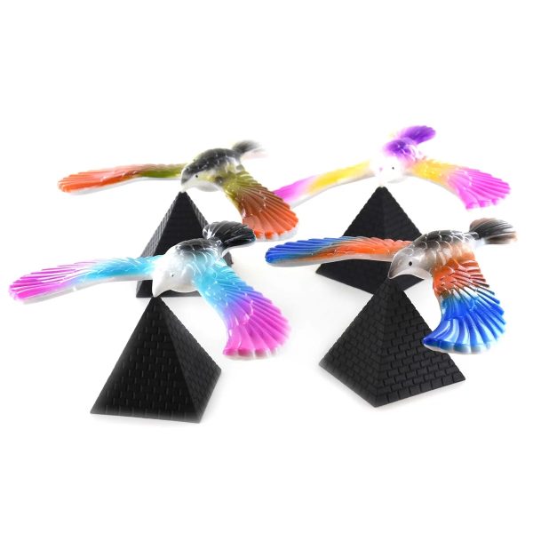 Балансираща цветна птица върху черна пирамида.